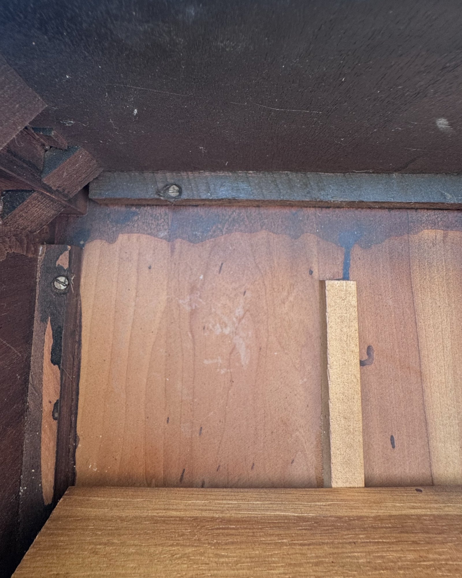 Close-up of an antique side table with a small rectangular piece of wood.