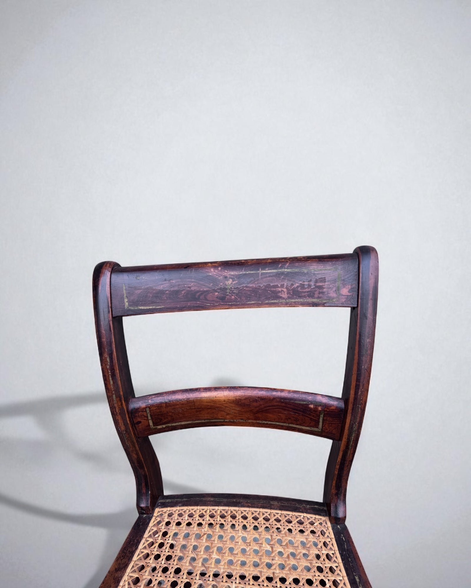 Caned dining chairs with a woven seat against a plain background