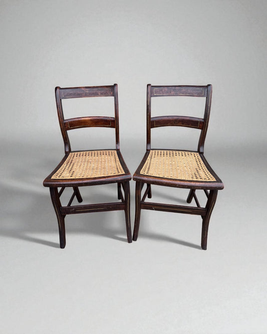Two wooden caned dining chairs with wicker seats on a gray background