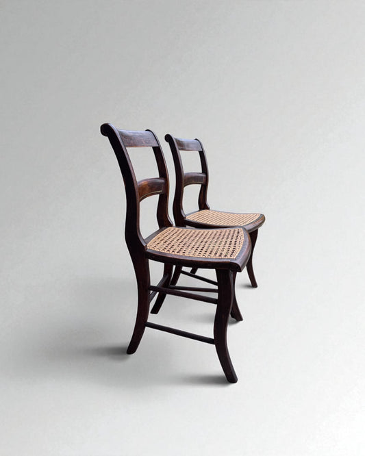 Pair of caned dining chairs with woven seats on a light gray background