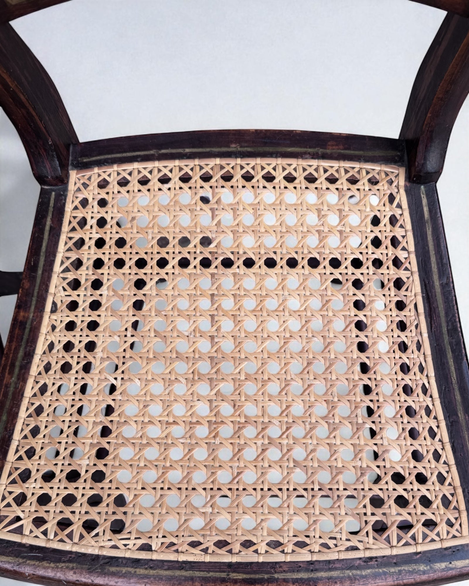 Close-up of a caned dining chair seat with woven cane pattern on a white background