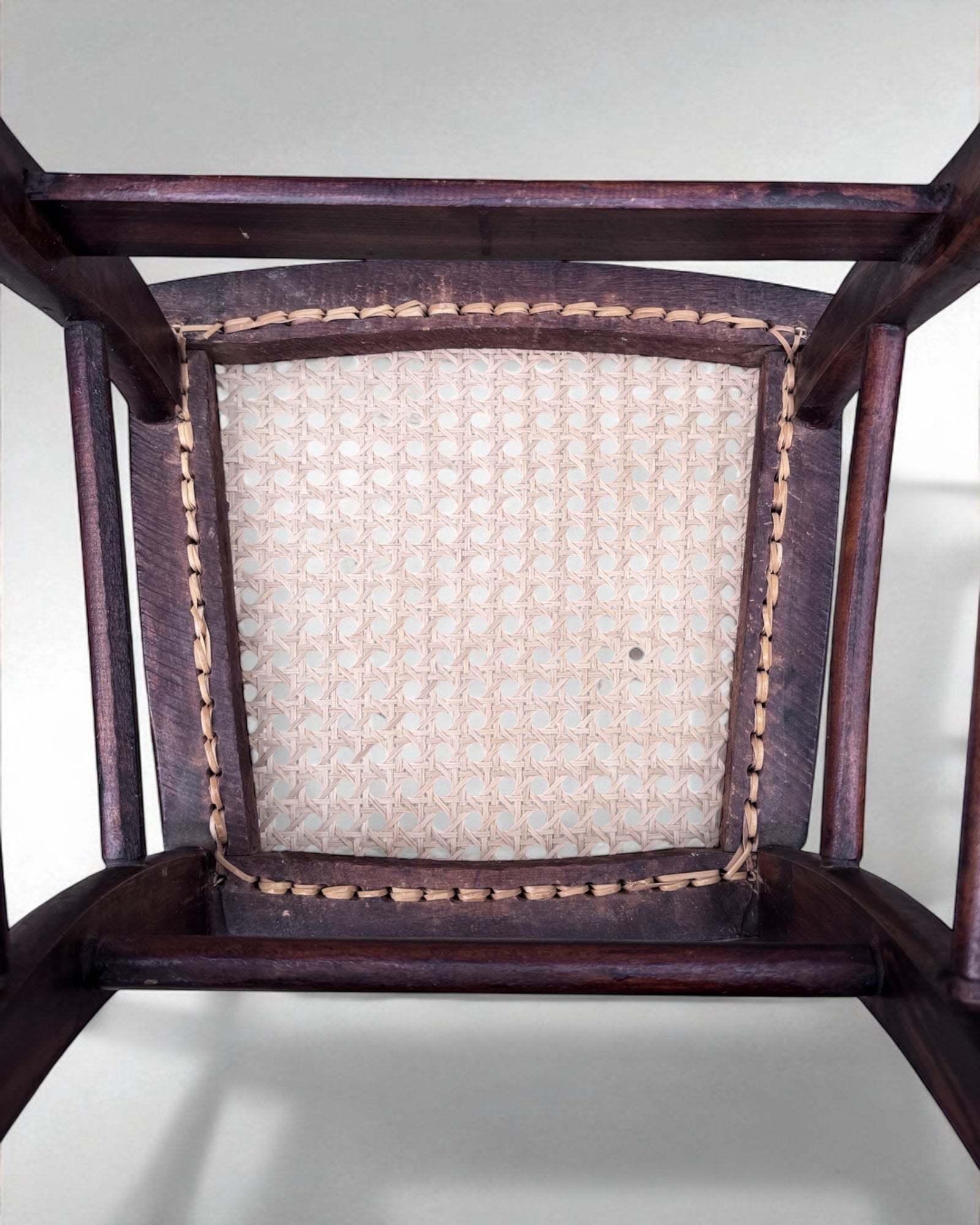 Close-up of a wooden caned dining chair with a woven seat on a white background
